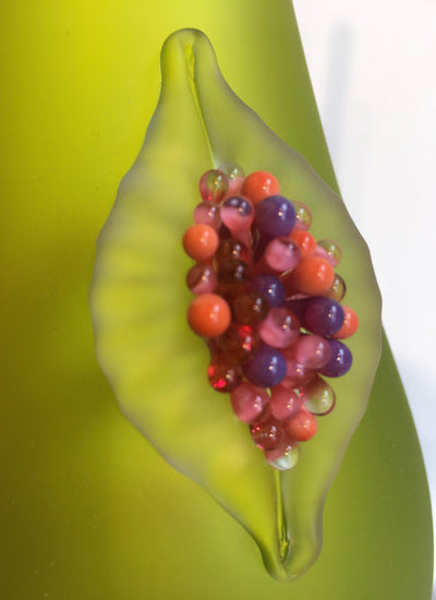Vase en verre vert avec une figue rouge.