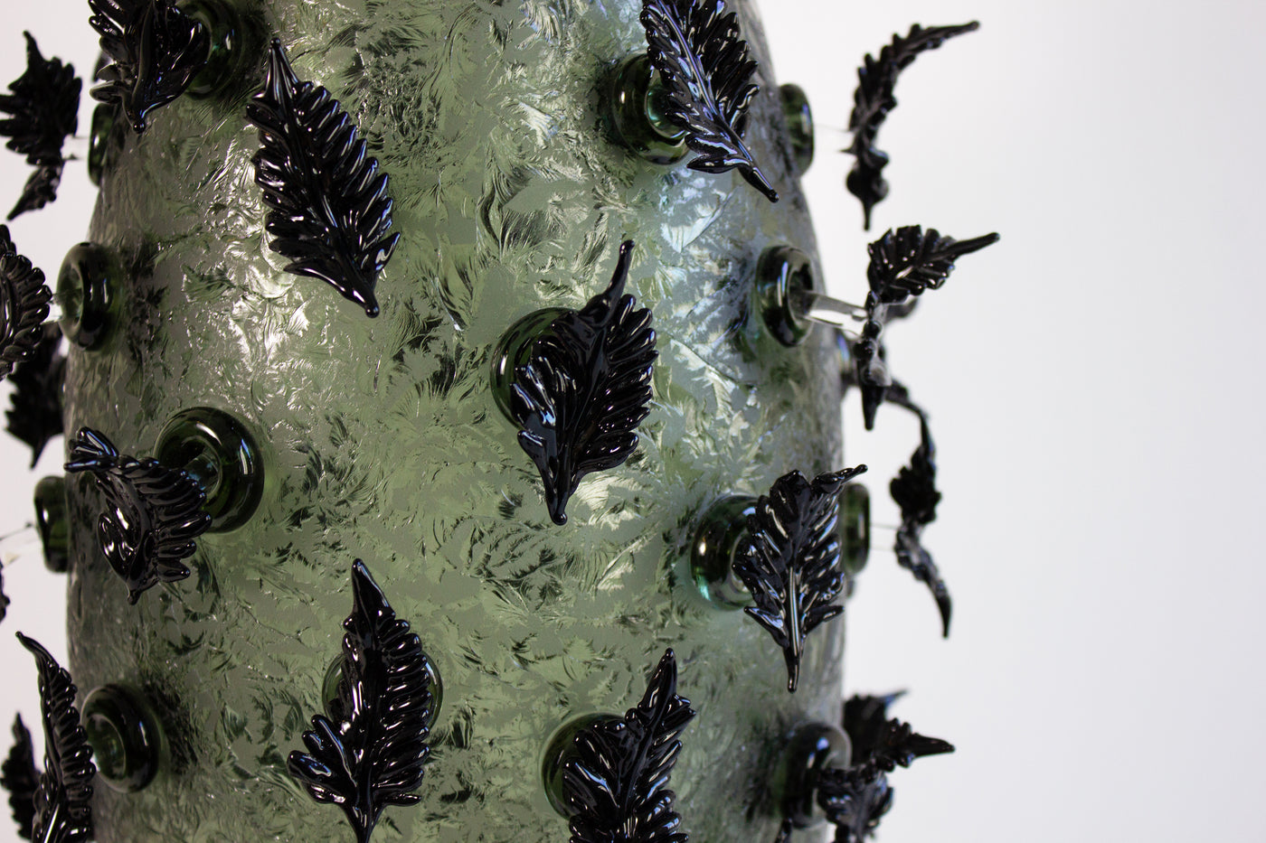 Sculpture en verre soufflé de la chrysalide avec des feuilles noires.