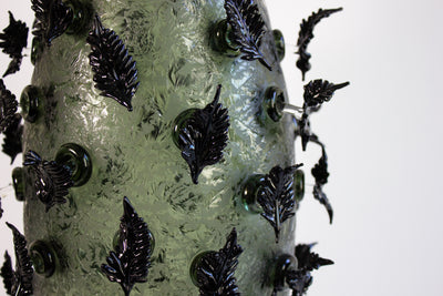 Sculpture en verre soufflé de la chrysalide avec des feuilles noires.