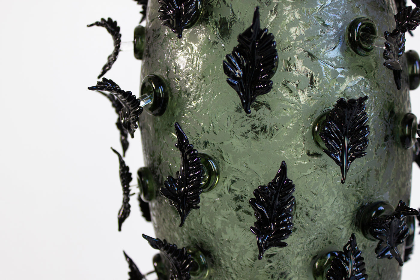 Sculpture en verre soufflé de la chrysalide avec des feuilles noires.