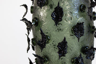 Sculpture en verre soufflé de la chrysalide avec des feuilles noires.
