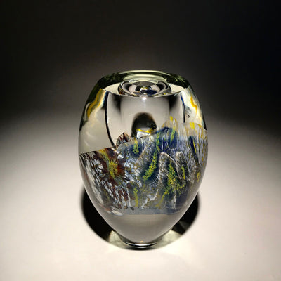 Sculpture d'un vase de couleur transparent, blanc, bleu, jaune et autres réalisé en verre soufflé travaillé à froid par l'artiste Maryse Chartrand de Sutton, Québec, Canada.