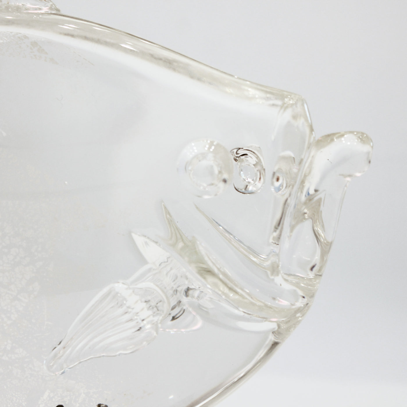 Sculpture en verre d'un poisson soutenu par une structure en métal.