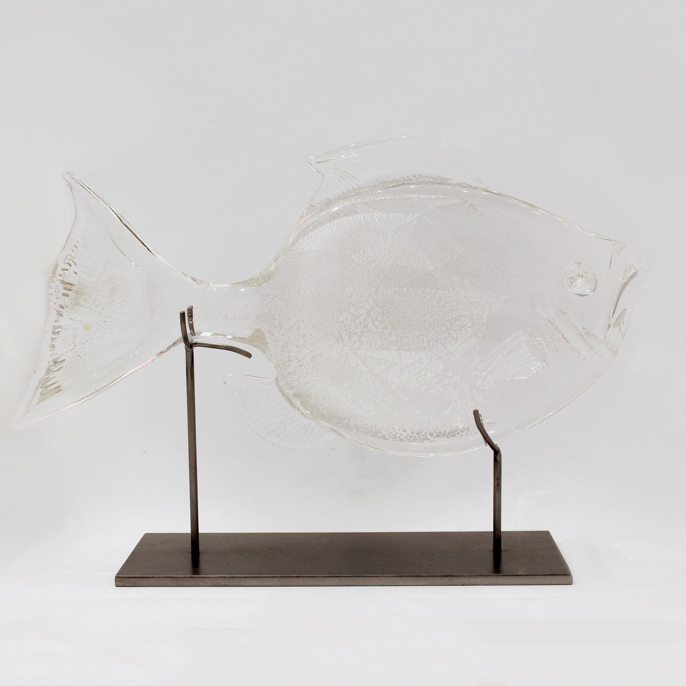 Sculpture en verre d'un poisson soutenu par une structure en métal.